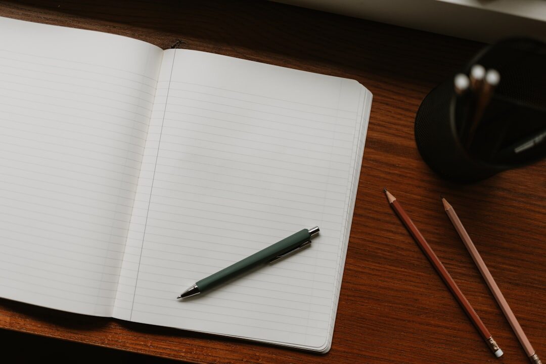 Open notebook next to a laptop on a wooden desk