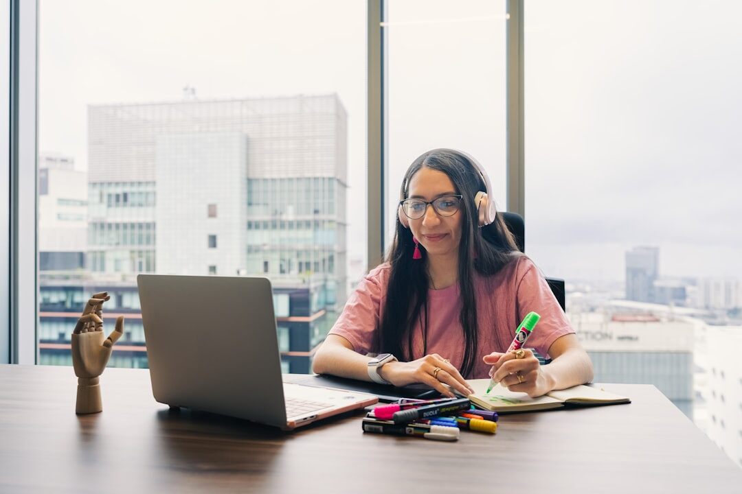 Journalist writing notes at a desk with a laptop